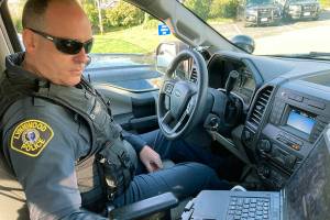 Lynnwood police Officer Denis Molloy works in his vehicle, Wednesday, Nov. 17, 2021, in Lynnwood, Wash. Molloy, of the Lynnwood Police Department's community health and safety section, says that navigating recent police reforms in Washington State has been challenging. (AP Photo/Gene Johnson)