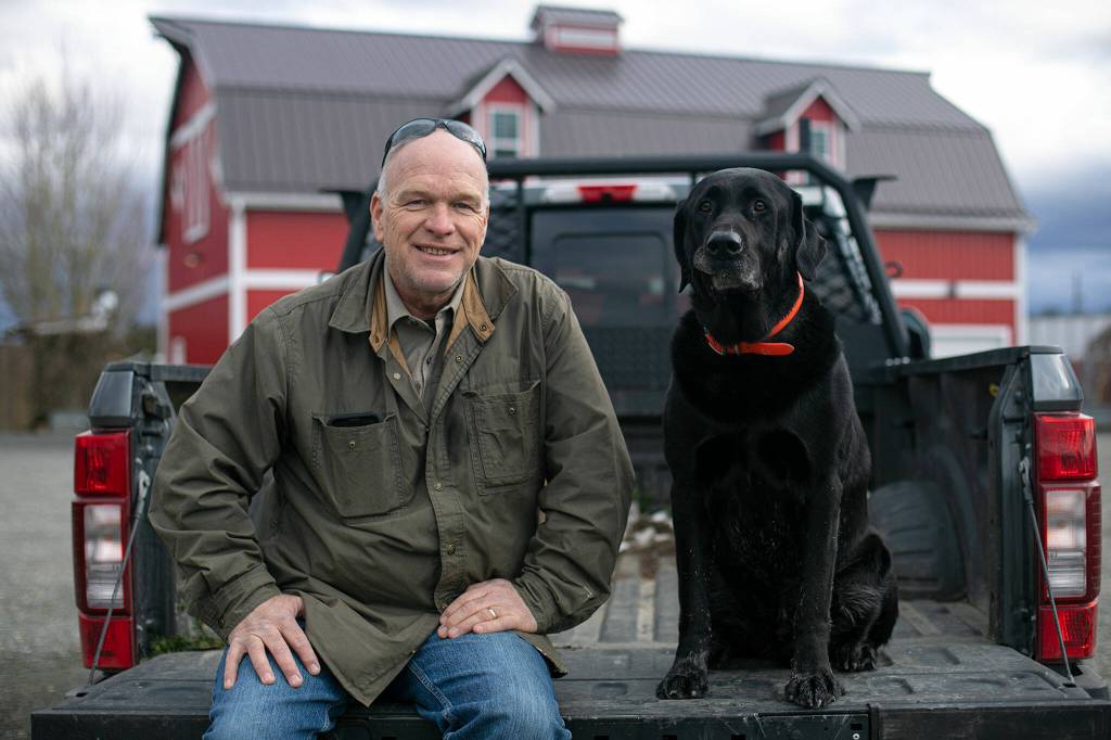 Keith Stocker and his black lab, Tango, at Stocker Farms in Snohomish. (Ryan Berry / The Herald)