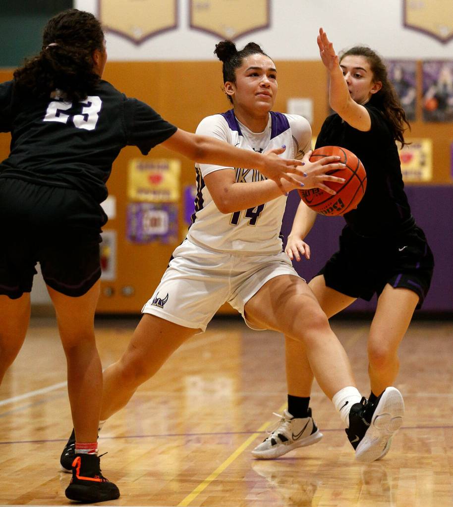 Lake Stevens Baylor Thomas splits two defenders against Kamiak Monday, Feb. 7, 2022, at Lake Stevens High School in Lake Stevens, Washington. (Ryan Berry / The Herald)