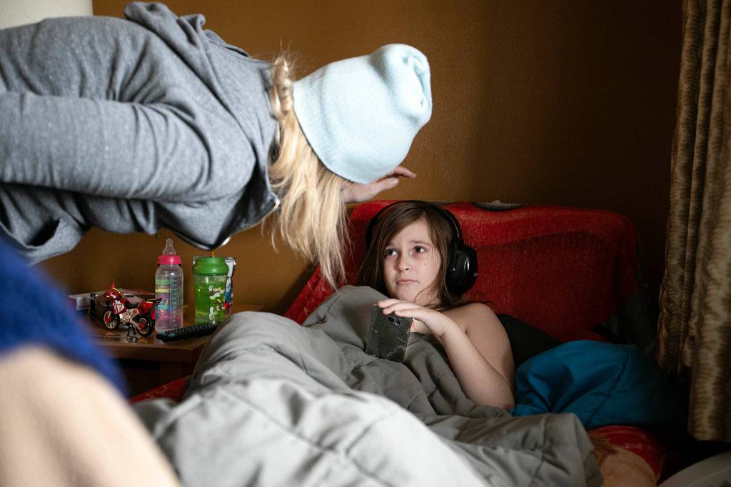 Melinda Parke comforts her 8-year-old son, Elijah, while he watches television at the Days Inn in Everett. (Ryan Berry / The Herald)