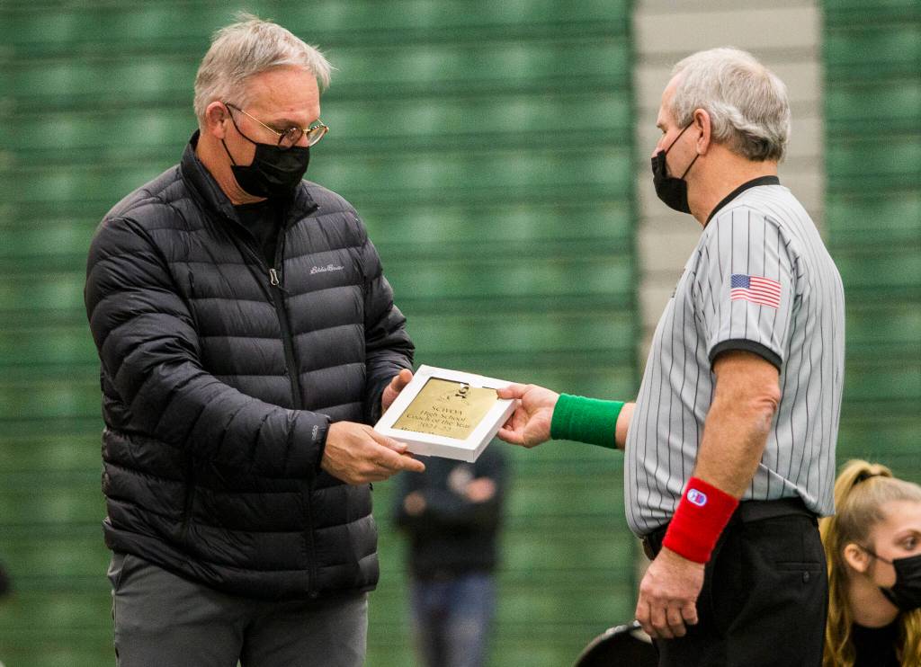 Lake Stevens head wrestling coach Brent Barnes (left) receives the SCWOA High School Coach of the Year award from the officials at the Wesco 4A sub-regional tournament at Henry M. Jackson High School on Feb. 5 in Everett. (Olivia Vanni / The Herald)