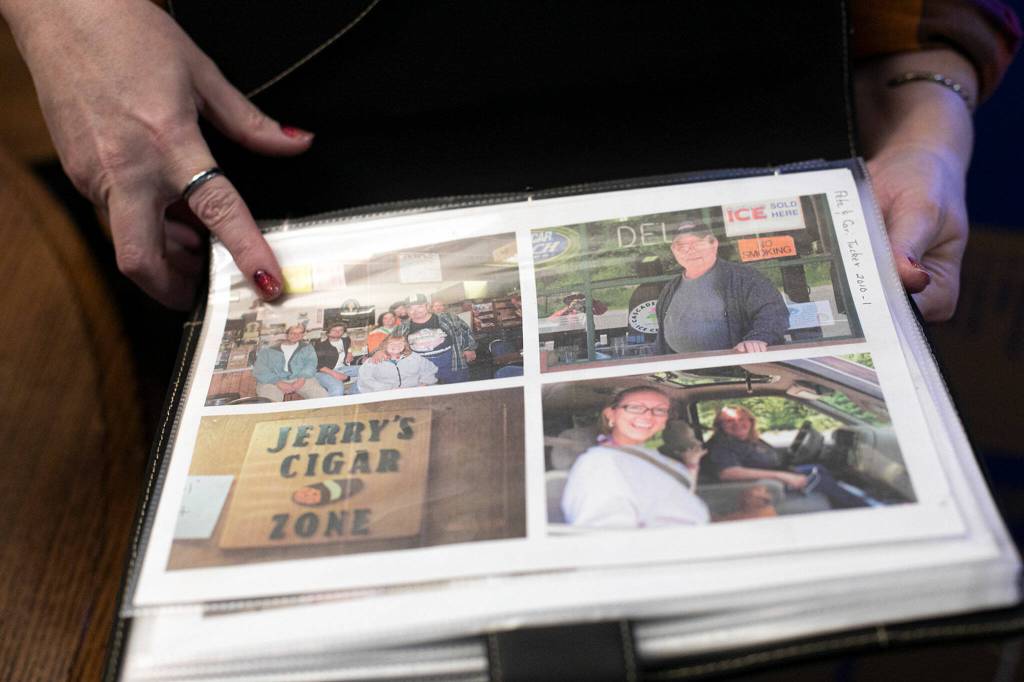 Diane Altman Jennings shows off photos of her father, Jerry Dinsmore (top right), and other friends and family. (Ryan Berry / The Herald)
