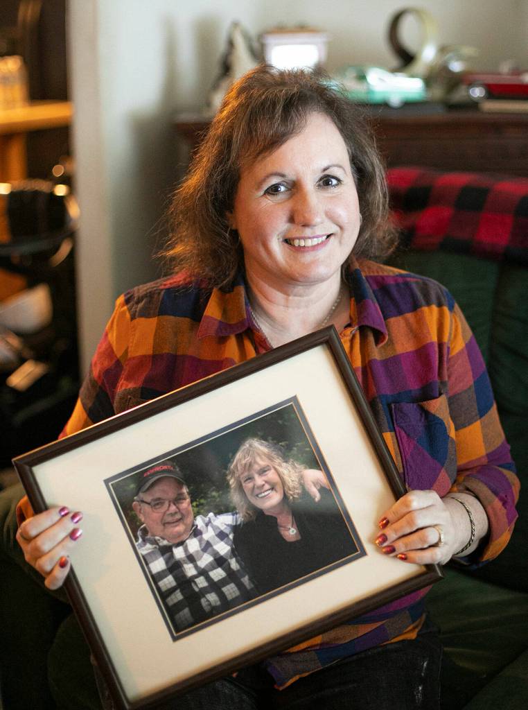 Diane Altman Jennings holds a photo of her father, Jerry Dinsmore, and his wife, Andrea. (Ryan Berry / The Herald)