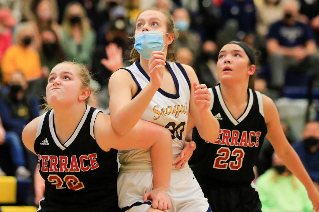 Mountlake Terraces Ainslee Beach, left, and Elise Colvin work box out Everetts Caroline Jameson, center, Friday evening in Everett, Washington on February 11, 2022. (Kevin Clark / The Herald)