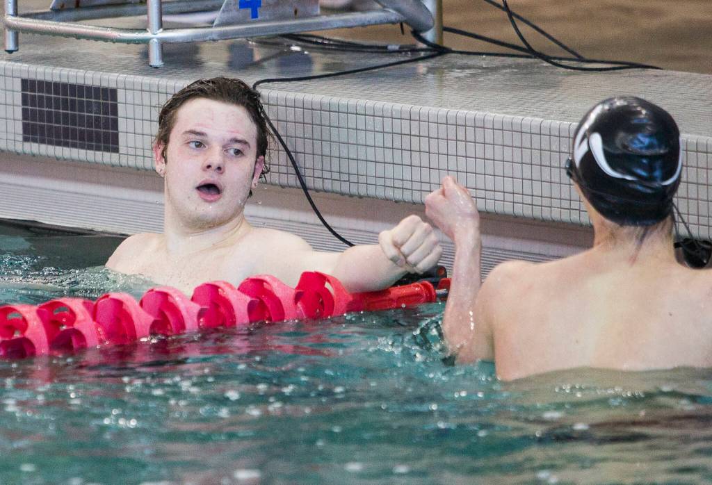Lake StevensՠGarrett Chesley fist bumps Reece Gerhart after winning the the 100 Yard Backstroke during the 4A Boys Districts swim meet on Saturday, Feb. 12, 2022 in Snohomish, Wa. (Olivia Vanni / The Herald)