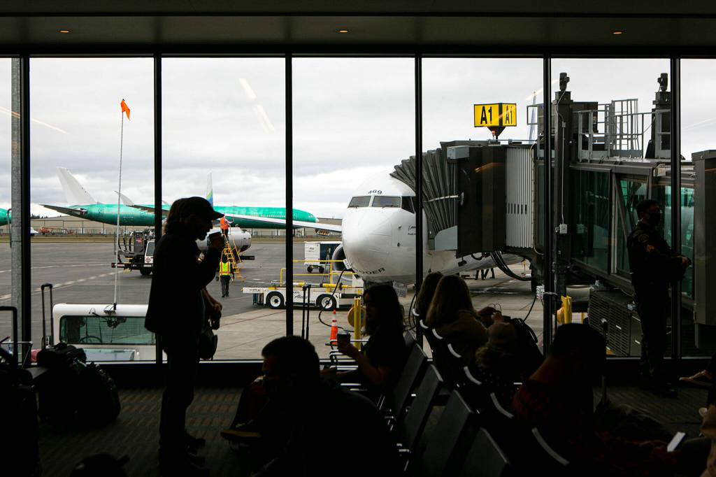 Flyers wait to become the first passengers to depart on a Boeing 737 from Paine Field on Thursday in Everett. (Ryan Berry / The Herald)