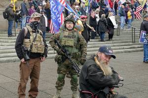 In this photo taken Jan. 6, 2021 at the Capitol in Olympia, Wash., two men stand armed with guns at a protest supporting President Donald Trump and against the counting of electoral votes in Washington, DC, affirming President-elect Joe Biden's victory. The open carry of guns and other weapons would be banned on the Washington state Capitol campus and at or near any public demonstration across Washington under a measure that received a remote public hearing Tuesday, Jan. 26, 2021 by the Senate Law and Justice Committee. (AP Photo/Ted S. Warren)