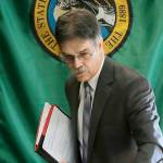 Steve Lerch, executive director of the Washington state Economic and Revenue Forecast Council, walks in front of the Washington state flag, Wednesday, Feb. 19, 2020, following a meeting of the council at the Capitol in Olympia, Wash. Lawmakers were told that the state's latest revenue forecast shows they have significantly more money to work with as they prepare to unveil their supplemental state budget proposals. (AP Photo/Ted S. Warren)