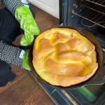 Herald food reporter Taylor Goebel pulls the finished Dutch baby from her oven. (Video screenshot / The Herald)