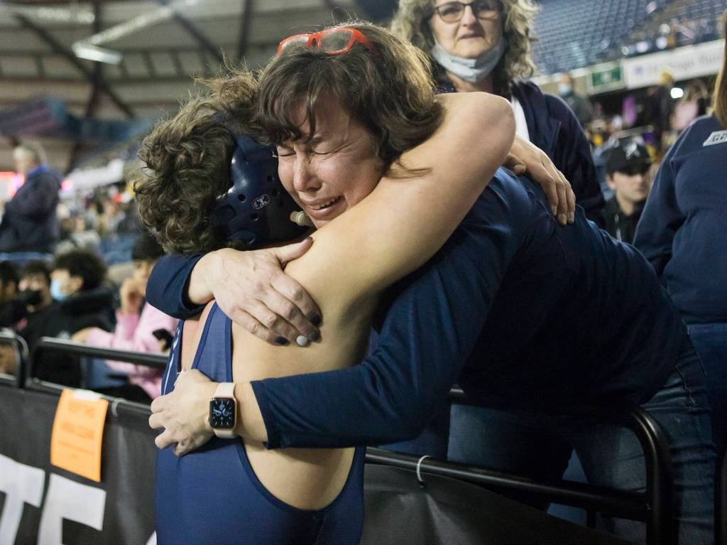 Glacier Peaks Jacob Erickson is hugged after winning the 4A 220-pound championship match during the Mat Classic XXXIII on Saturday in Tacoma. (Olivia Vanni / The Herald)