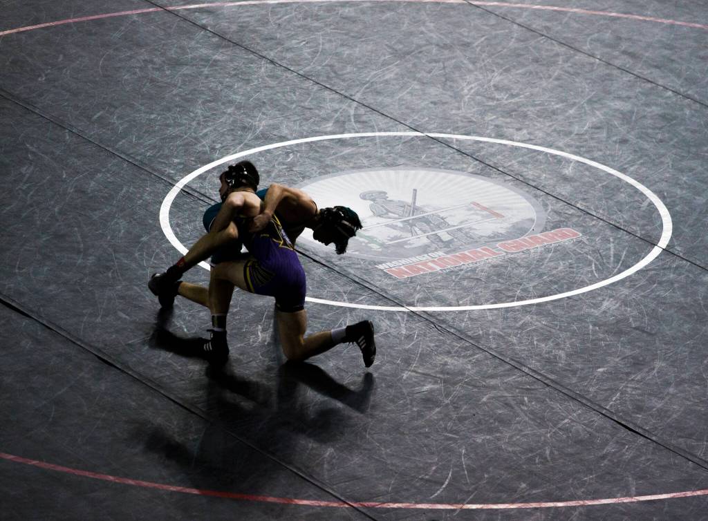 Wrestlers are silhouetted against a black wrestling mat during the Mat Classic XXXIII on Saturday in Tacoma. (Olivia Vanni / The Herald)