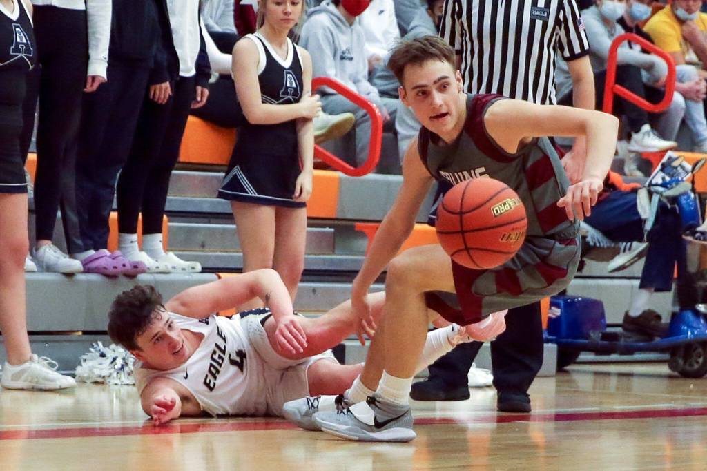 Cascades Aidan Kopra chases down a loose ball with Arlingtons Grayson Falk looking on Saturday afternoon at during the 3A District Tournament at Everett Community College in Everett, Washington on February 19, 2022. (Kevin Clark / The Herald )