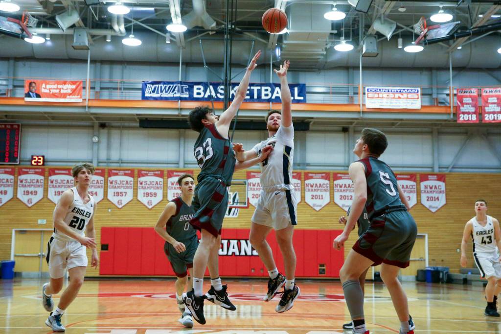 Arlingtons Luke Brown attempts a shot with Cascades Jackson Nelson defending Saturday afternoon at during the 3A District Tournament at Everett Community College in Everett, Washington on February 19, 2022. (Kevin Clark / The Herald )