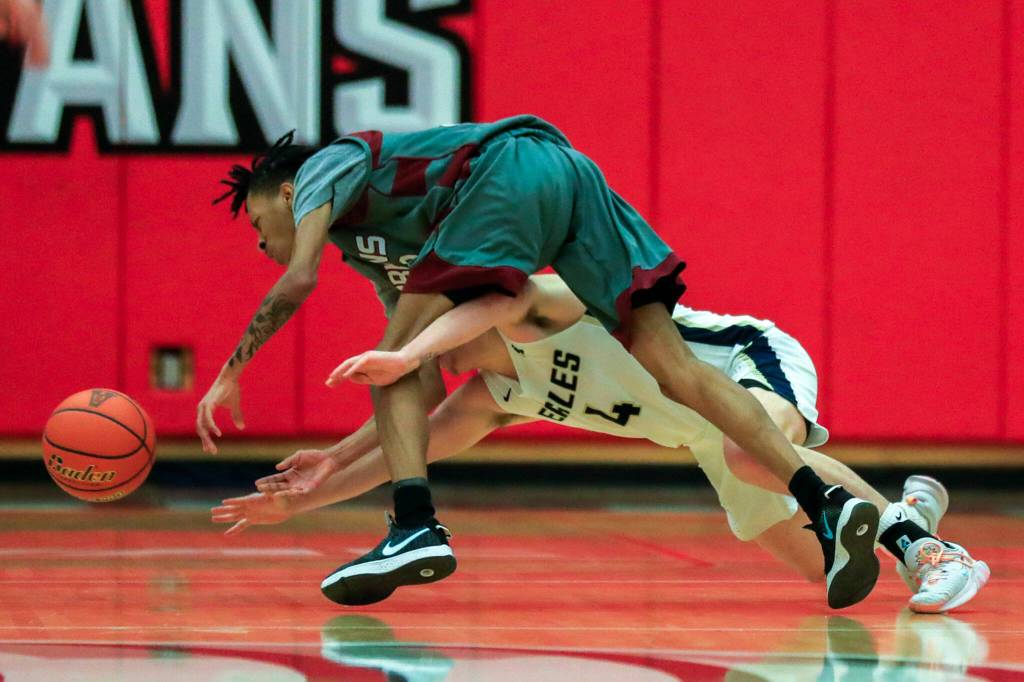 Cascades Abdoulie Cam is fouled by Arlingtons Grayson Falk during a steal Saturday afternoon at during the 3A District Tournament at Everett Community College in Everett, Washington on February 19, 2022. (Kevin Clark / The Herald )