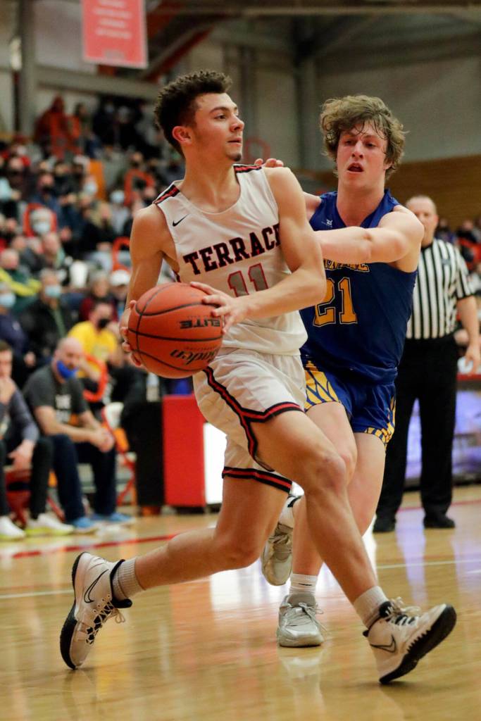 Mountlake Terraces Chris Meegan drives the baseline with Ferndales Conner Walcker reaching in Saturday evening at during the 3A District Tournament at Everett Community College in Everett, Washington on February 19, 2022. (Kevin Clark / The Herald )