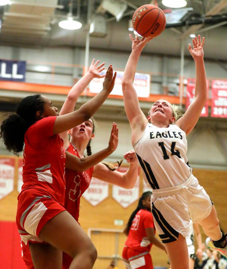 Arlingtons Keira Marsh drives the lane for contested layup against Stanwood Saturday evening at during the 3A District 1 Title game at Everett Community College in Everett, Washington on February 19, 2022. (Kevin Clark / The Herald )