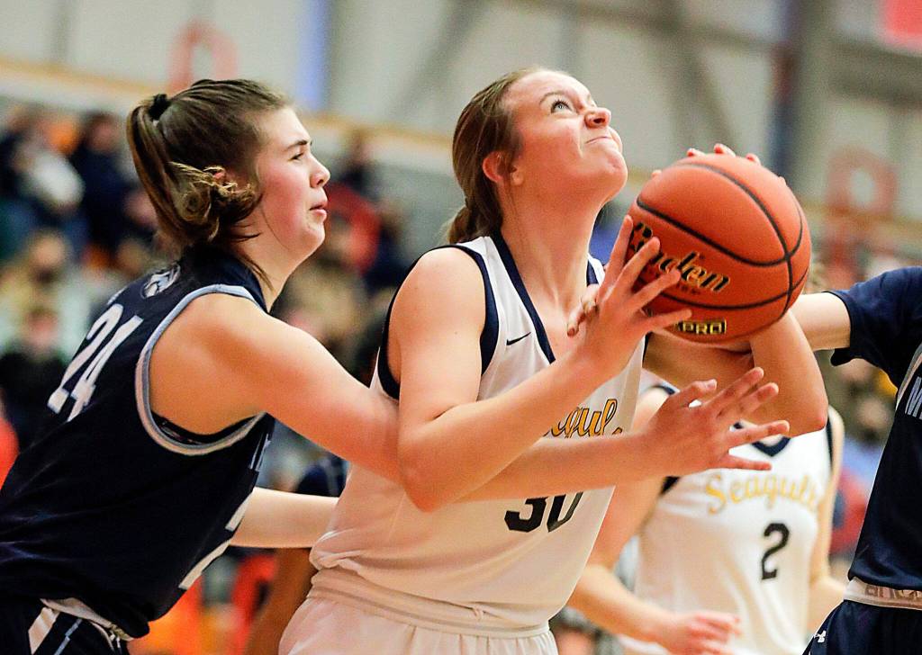 Everetts Caroline Jameson looks to score with Meadowdales Ava Powell reaching in Saturday afternoon at during the 3A District Tournament at Everett Community College in Everett, Washington on February 19, 2022. (Kevin Clark / The Herald )