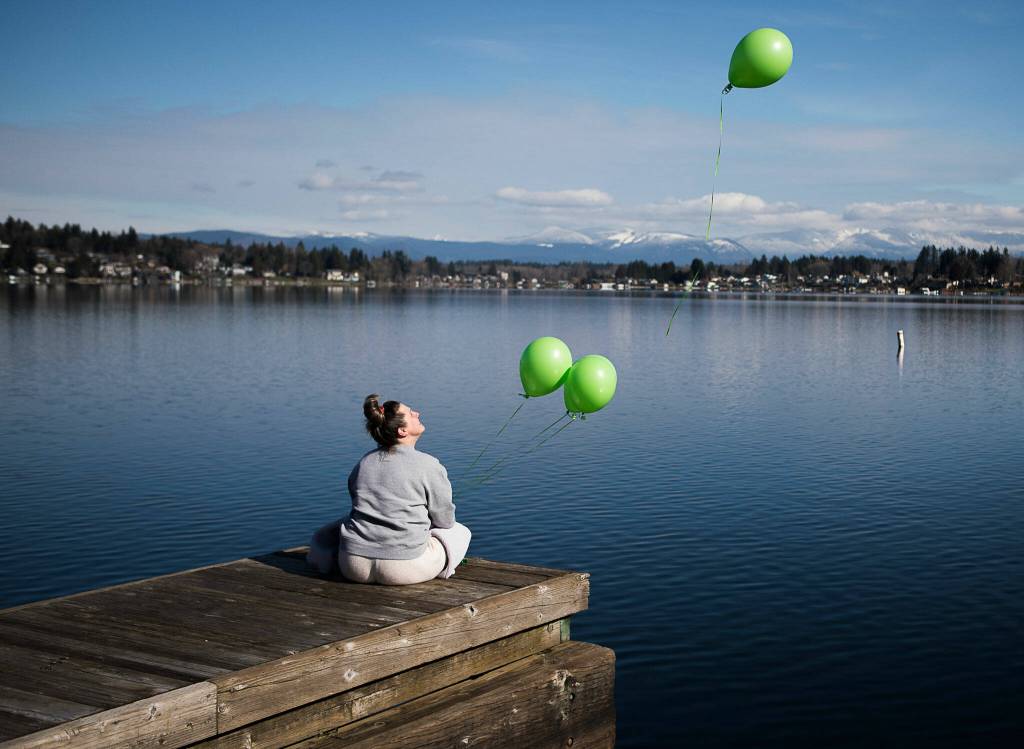 Ashley Olson releases green balloons from the dock at Davies Beach in Lake Stevens in memory of her brother, Joey Mell, who overdosed a year ago. Green was Mells favorite color and Olson describes her brother as gorgeous and a real thrill seeker due to his job as a highline tree trimmer. (Olivia Vanni / The Herald)