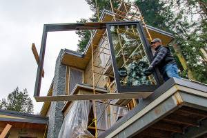 A construction crew prepares to install a window at a South Whidbey site. Photo by Dave Welton