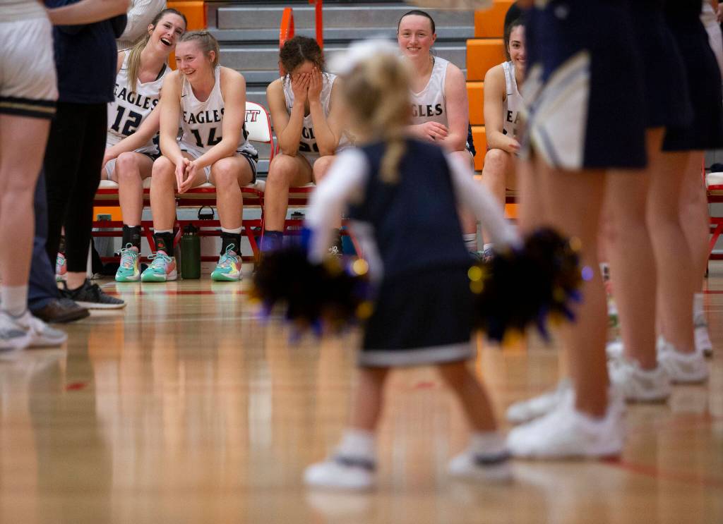 The Arlington bench reacts to a young girl dressed as a cheerleader shaking her pompoms at them before the start of the game. (Olivia Vanni / The Herald)