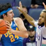 UCLA guard Jaime Jaquez Jr. (24) looks to pass around the defense of Washington guard PJ Fuller, right, during the first half of an NCAA college basketball game, Monday, Feb. 28, 2022, in Seattle. (AP Photo/Ted S. Warren)