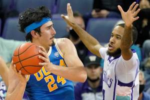 UCLA guard Jaime Jaquez Jr. (24) looks to pass around the defense of Washington guard PJ Fuller, right, during the first half of an NCAA college basketball game, Monday, Feb. 28, 2022, in Seattle. (AP Photo/Ted S. Warren)