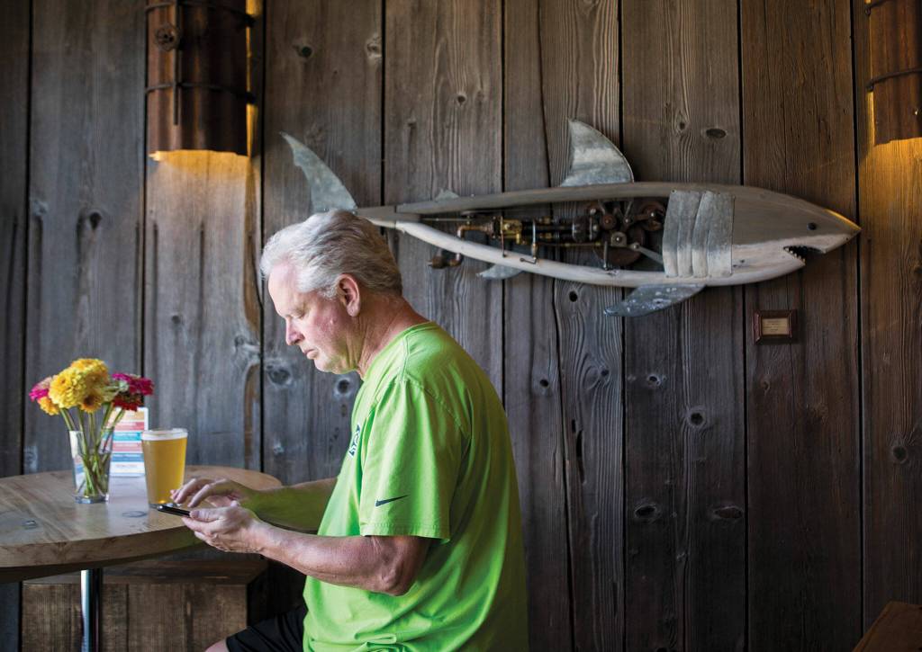 A customer enjoys a beer next to wall art by a local artist. (Olivia Vanni / The Herald)