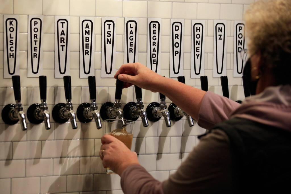 A Salish Sea Brewing employee draws a beer at The Boathouse on Nov. 24. (Kevin Clark / The Herald)