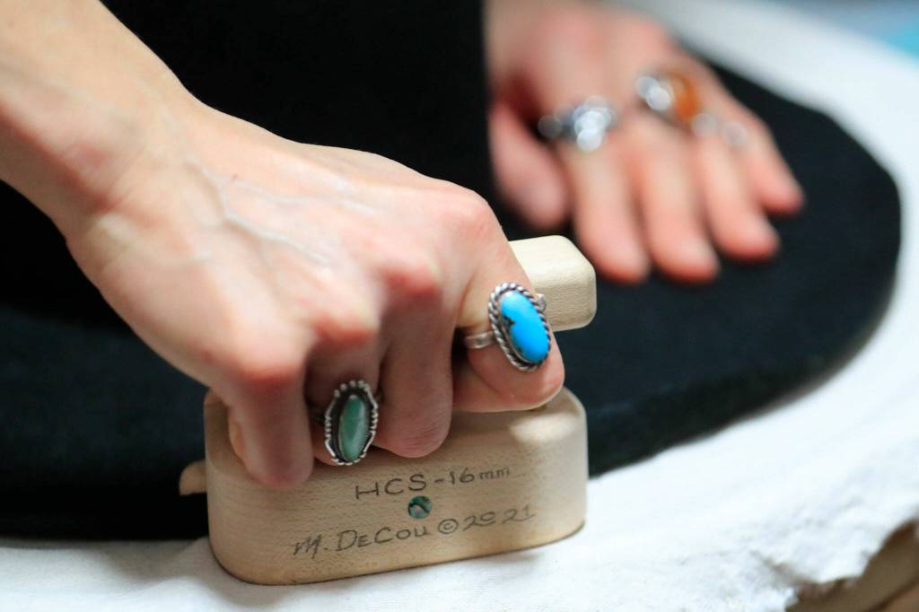 Jac Cash adds a lip to a hat at the FauxyFurr manufacturing shop in Arlington. (Kevin Clark / The Herald )