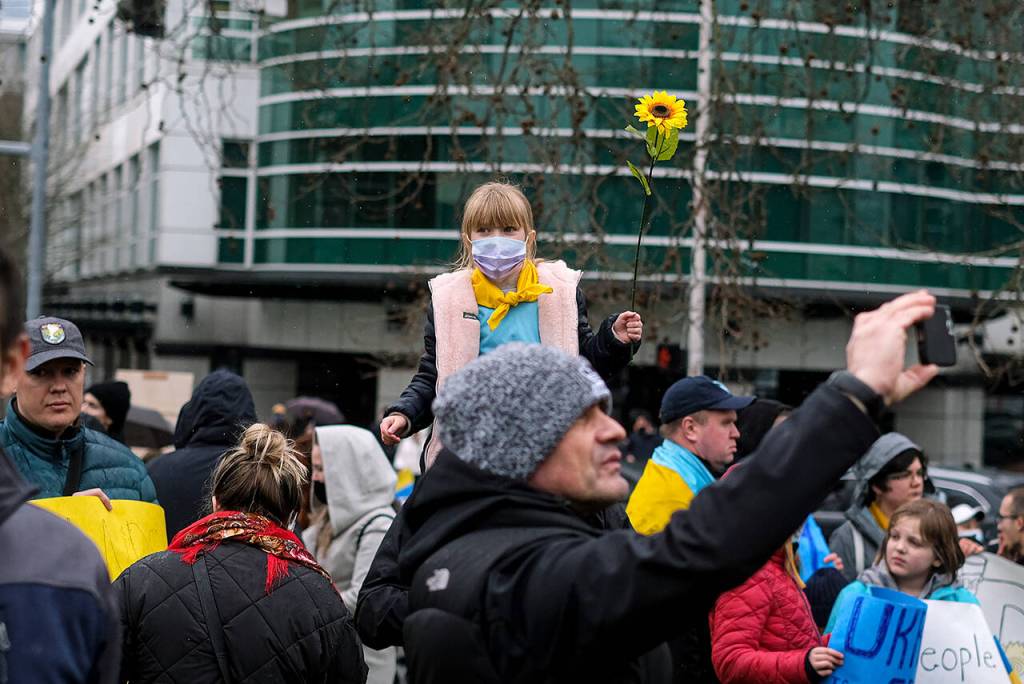 A young child carries a sunflower, the national flower of Ukraine, during a demonstration in Seattle on Saturday. The sunflower became a symbol against Russias invasion after a Ukrainian woman confronted a heavily armed Russian soldier last week. While cursing at the soldier, she offered him seeds so that when he died on Ukrainian soil, at least sunflowers will grow. (Taylor Goebel / The Herald)