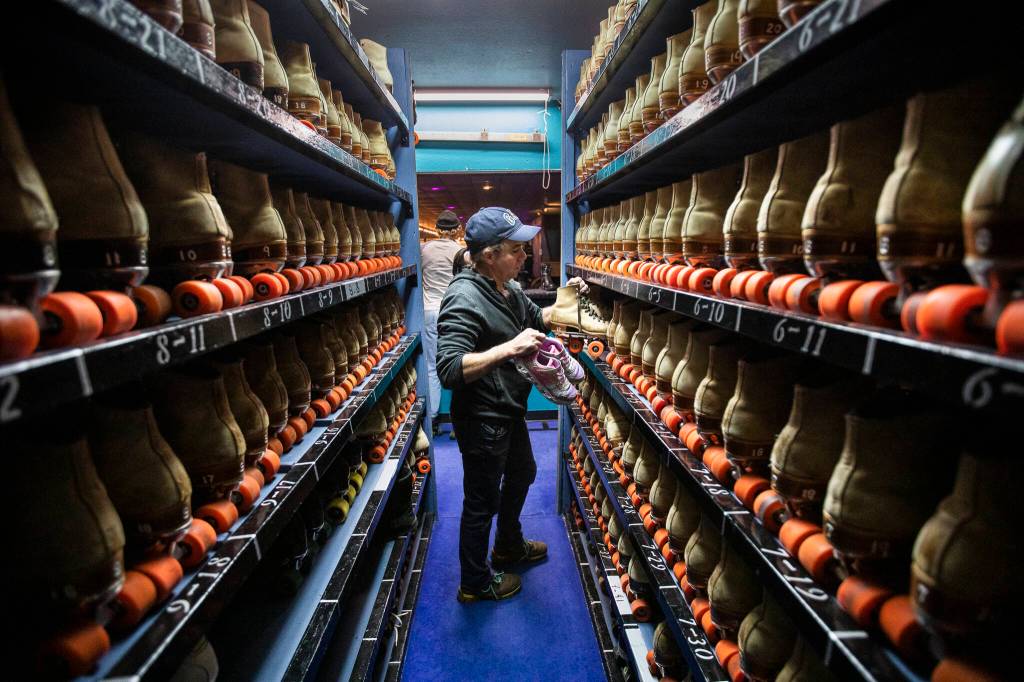 Yusmani Milo grabs a pair of skates for a customer Thursday at the Everett Skate Deck. Milo has worked in the skates room for over 20 years. (Olivia Vanni / The Herald)