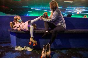 Courtney Simons, right, helps her daughter Whitaker, 5, get her skates on before heading out to the rink at Everett Skate Deck on Thursday, March 3, 2022 in Everett, Washington. (Olivia Vanni / The Herald)