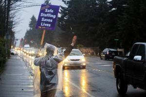 Vibal Vidal, a recovery nurse at Swedish Edmonds, pickets outside the hospital Tuesday morning. (Joey Thompson / The Herald)