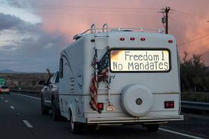 A trailer with the words "Freedom! No Mandate" on its back window travels with a trucker caravan heading toward Washington D.C. to protest COVID-19 mandates on Wednesday, Feb. 23, 2022, near Needles, Calif. (AP Photo/Nathan Howard)