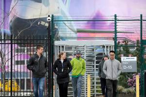 FILE - In this March 23, 2020, file photo, workers head out a gate at a Boeing airplane manufacturing plant, where a mural of a jet covers a massive door behind in Renton, Wash. Boeing Co. has said it will dole out annual performance bonuses next month to most employees despite losing $12 billion over the last year during the coronavirus pandemic. Most of the company's employees did not receive annual bonuses last year after it lost $636 million in 2019 because of the grounding of the 737 MAX by the Federal Aviation Administration, The Seattle Times reported. (AP Photo/Elaine Thompson, File)