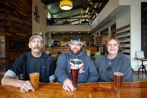 Kory Dyer, center, along with his parents, Kent and Tania Dyer, sit inside the dining room Friday, March 4, 2022, at Meatheads Smokehouse and Beer Works in Lake Stevens, Washington. (Ryan Berry / The Herald)