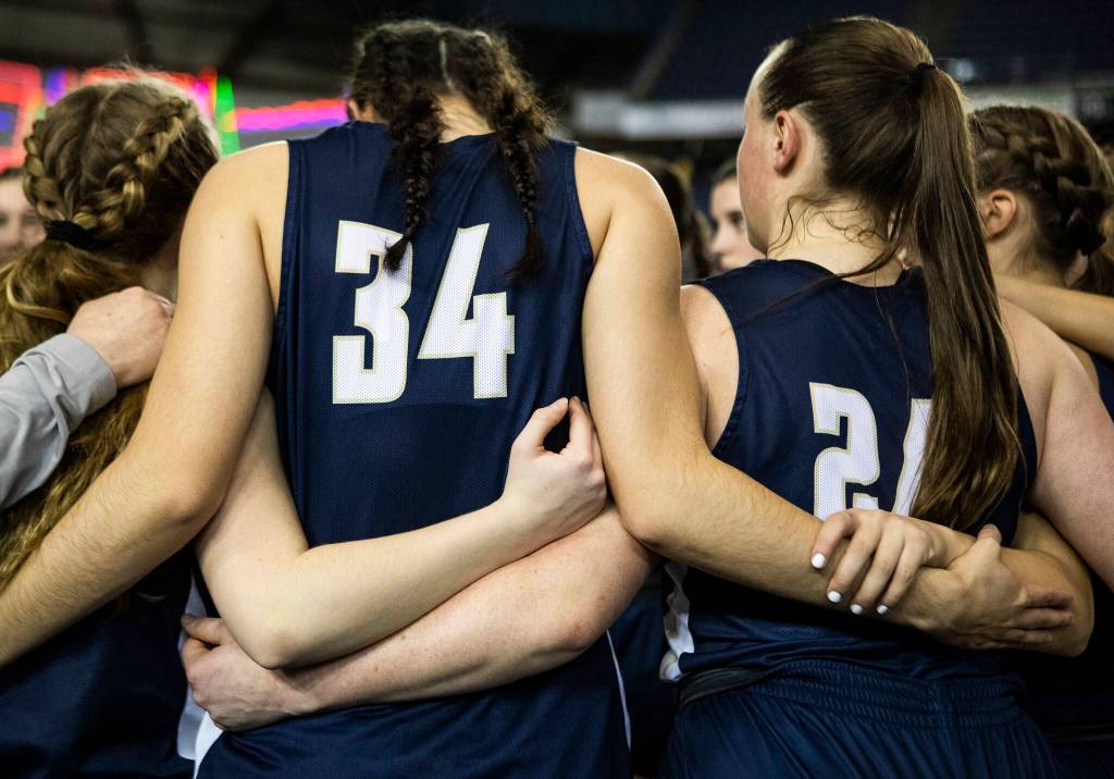 Arlington players link arms during a huddle before the start of the 3A state semifinal at the Tacoma Dome on Friday, March 4, 2022. (Olivia Vanni / The Herald)