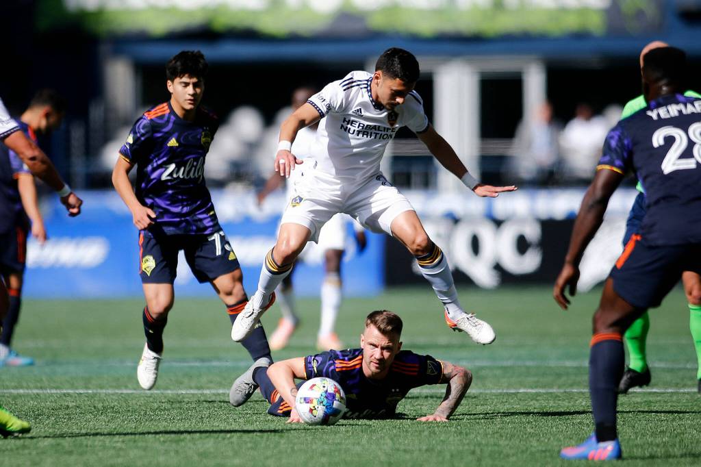 The Los Angeles Galaxys Mark Delgado leaps over an opponent during a game against the Sounders Saturday, March 12, 2022, at Lumen Field in Seattle, Washington. (Ryan Berry / The Herald)