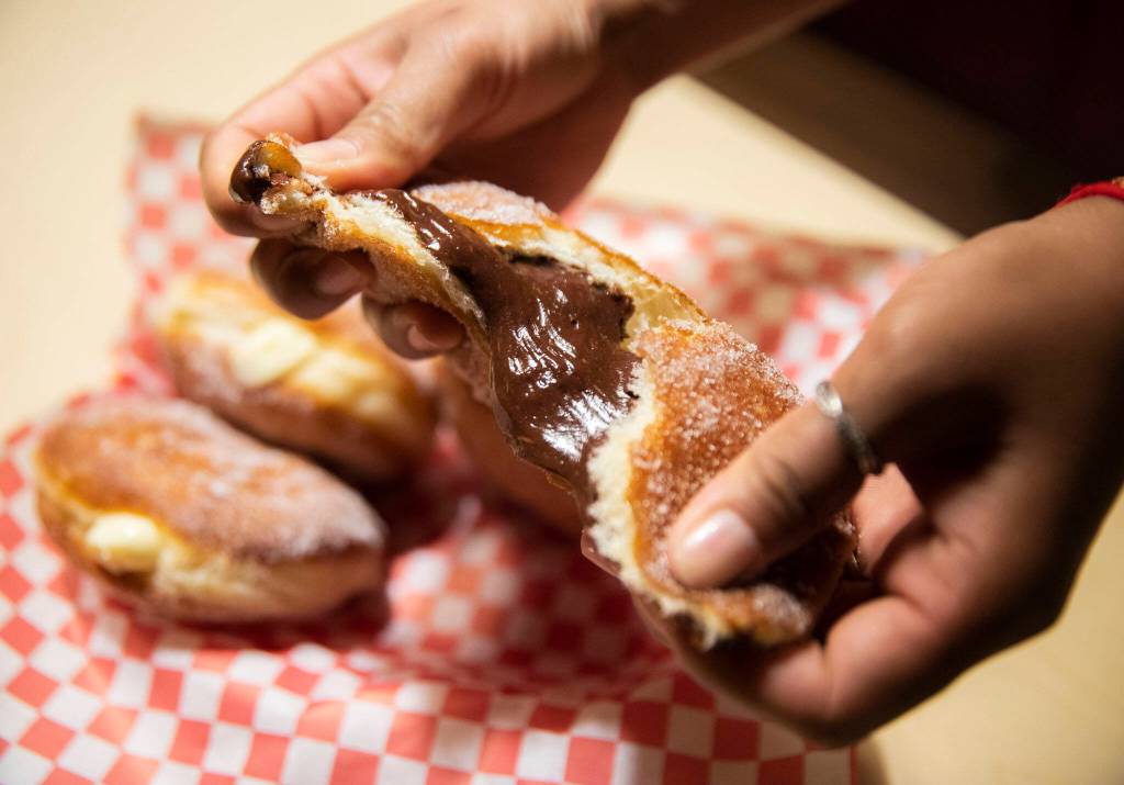 Sreylish Alice Tum rips open one of her chocolate pudding-filled malasadas. (Olivia Vanni / The Herald)