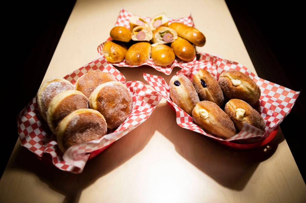 An assortment of sugar-covered-and-filled malasadas and sausage-filled kolaches. (Olivia Vanni / The Herald)