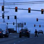 A man crosses the road under stoplights at Casino Road and Evergreen Way on Friday, Dec. 13, 2019 in Everett, Wash. The lights at Casino Road and Evergreen Way are being considered for controversial red-light traffic cameras. (Andy Bronson / The Herald)