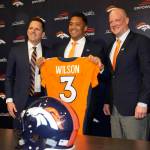 New Broncos quarterback Russell Wilson (center) holds up his jersey while flanked by head coach Nathaniel Hackett (right) and general manager George Paton after a news conference Wednesday in Englewood, Colo. (AP Photo/David Zalubowski)