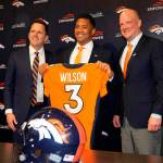 Denver Broncos new starting quarterback Russell Wilson, center, hods up his new jersey while flanked by head coach Nathaniel Hackett, right, and general manager George Paton after a news conference Wednesday, March 16, 2022, at the team's headquarters in Englewood, Colo. (AP Photo/David Zalubowski)