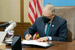 Washington Gov. Jay Inslee signs a measure that prohibits legal action against both people seeking an abortion and those who aid them, on Thursday, March 17, 2022 in Olympia, Wash. Inslee's signature comes days after the Legislature in neighboring Idaho approved a bill modeled on a law in Texas that allows lawsuits to enforce a ban on abortions performed after six weeks of pregnancy. (AP Photo/Rachel La Corte)