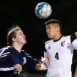 Arlingtons Jack Machovina watches Monroes Rafael Garnica heads the ball Friday evening at Arlington High School in Arlington, Washington on March 18, 2022. (Kevin Clark / The Herald)