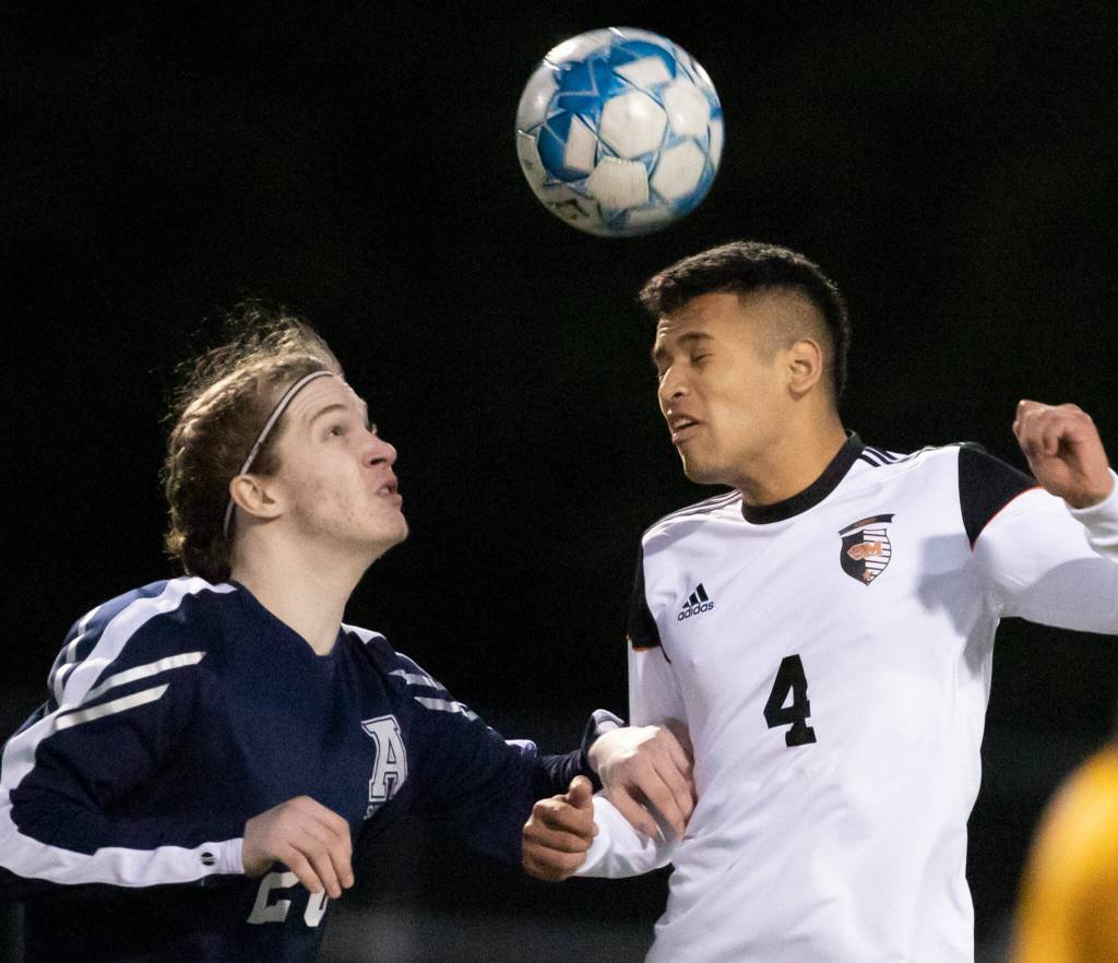 Arlingtons Jack Machovina watches Monroes Rafael Garnica heads the ball Friday evening at Arlington High School in Arlington, Washington on March 18, 2022. (Kevin Clark / The Herald)