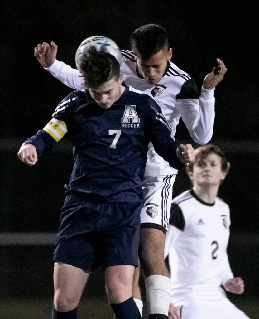 Arlingtons Cameron Mooring, front, and Monroes Rafael Garnica jump for a header Friday evening at Arlington High School in Arlington, Washington on March 18, 2022. (Kevin Clark / The Herald)