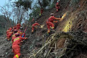 In this photo released by Xinhua News Agency, rescuers conduct search operations at the site of a plane crash in Tengxian County in southern China's Guangxi Zhuang Autonomous Region, Tuesday, March 22, 2022. Mud-stained wallets. Bank cards. Official identity cards. Some of the personal effects of 132 lives presumed lost were lined up by rescue workers scouring a remote mountainside Tuesday for the wreckage of a China Eastern plane that one day earlier inexplicably fell from the sky and burst into a huge fireball. (Zhou Hua/Xinhua via AP)