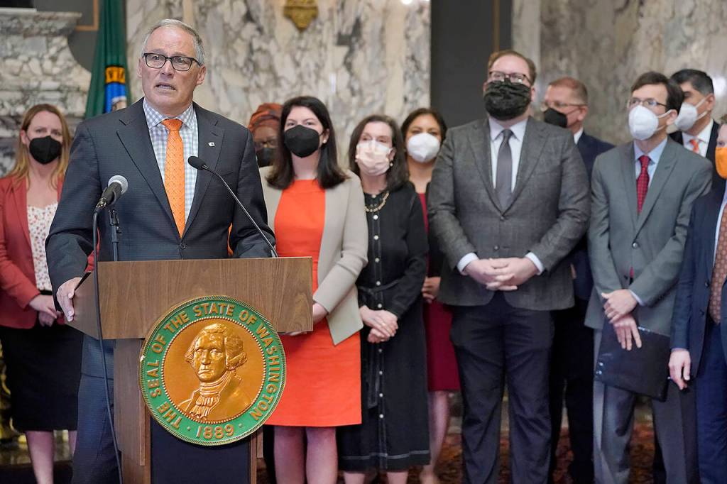Washington Gov. Jay Inslee (left) speaks at the podium with supporters and lawmakers behind him, including Sen. Marko Liias of Mukilteo (second from right), before signing a package of bills to tighten gun laws in Washington state, Wednesday at the Capitol in Olympia. (AP Photo/Ted S. Warren)