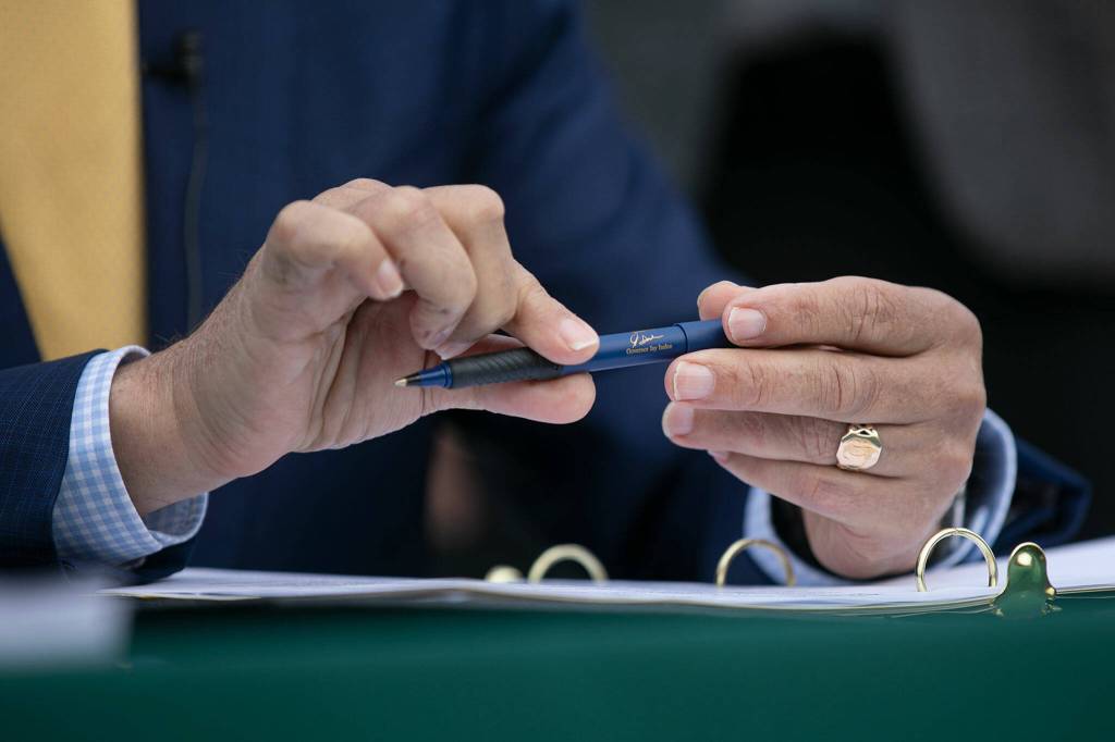 Governor Jay Inslee prepares to sign a number of bills into law during. (Ryan Berry / The Herald)
